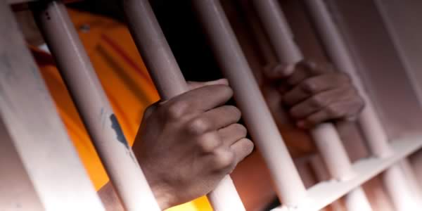 mans hands on jail cell bars
